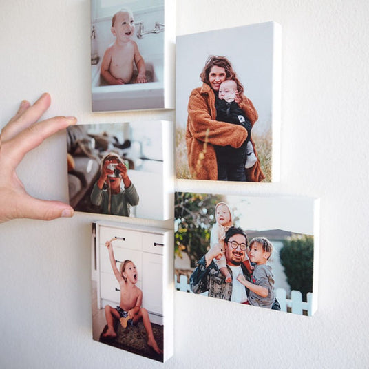 Collection of family photos printed on stone tiles and displayed in a collage on the wall